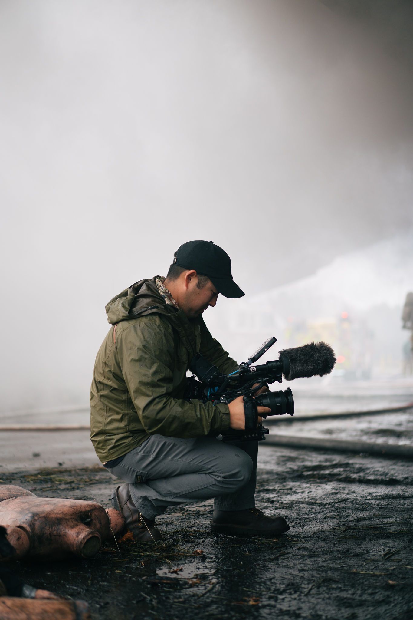 Nate kneels with a cinema camera in the smoke at a live fire training