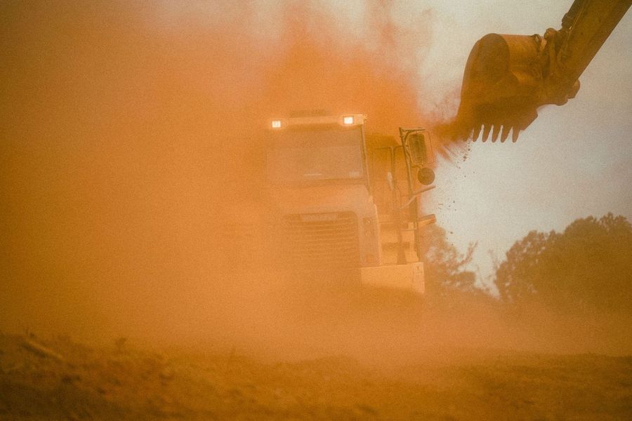 An excavator works in a wall of orange dust
