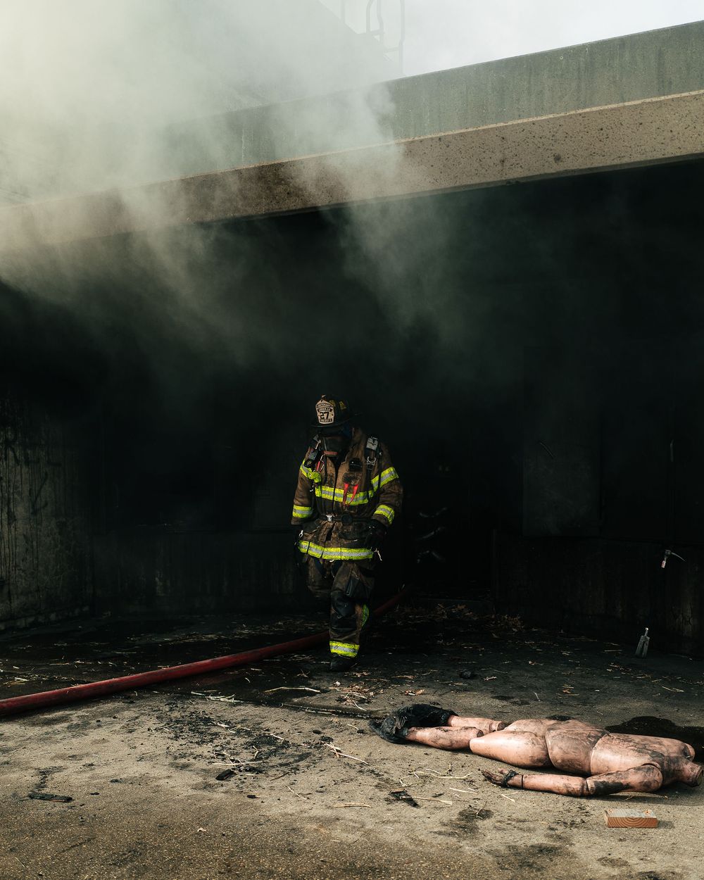 A firefighter in turnout gear walks out of smoke during a live training evolution